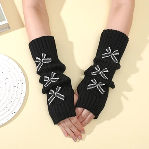 Detail of black knit arm warmers featuring ribbed texture and three striped bows decoration