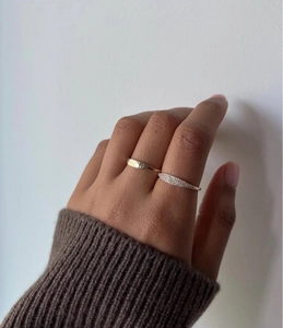 Dettaglio di un anello in acciaio placcato oro 18k con zirconi AAA su mano femminile
