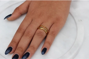 Primer plano de un anillo de doble capa en acero inoxidable dorado en el dedo de una modelo