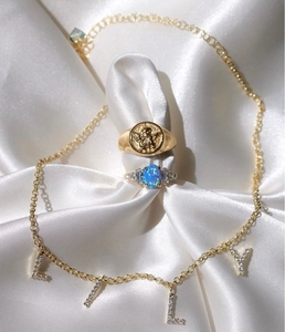 Anello con sigillo dorato con rilievo di angelo e set di anelli in opale su raso bianco