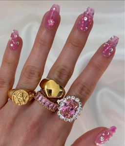 Dettaglio di anelli placcati oro 18K con rilievo d'angelo, cuore e pietre rosa