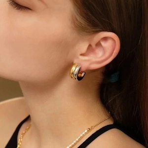 Detalle de aretes de aro bicolor en forma de C dorados y plateados en modelo femenino