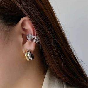 Primer plano de pendientes bicolores en forma de C con circonitas en oreja