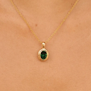 Macro-opname van een gouden roestvrijstalen ketting met ovale groene edelsteen hanger