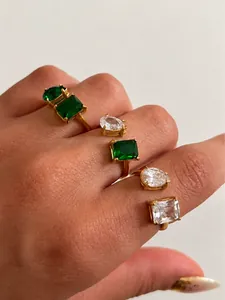 Detail van 18k vergulde roestvrijstalen ringen met groene en heldere zirkonia stenen