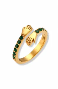 Dettaglio dell'anello abbraccio placcato oro 18K con pietre di zircone verde e mani