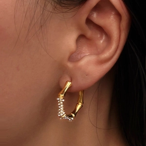 Vista macro de pendientes de bambú en oro de 18K con delicados detalles de circonitas