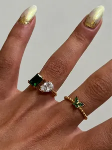 Detailopname van 18k vergulde ringen met groene smaragd en druppelvormige zirkonia