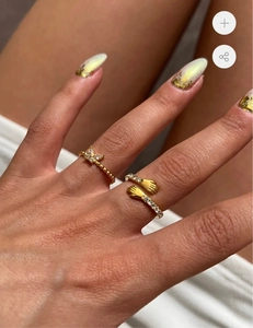 Dettaglio di anelli in acciaio al titanio placcati oro 18K con mani abbracciate e zirconi