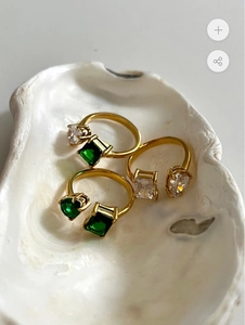 Gedetailleerd beeld van 18k vergulde verstelbare ringen met groene en witte zirkonia