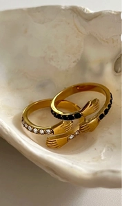 Dettaglio di anelli a mani che abbracciano placcati oro 18K con zirconi bianchi e neri