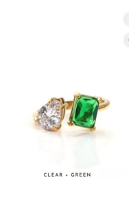 Gedetailleerde weergave van gouden open ring met heldere en groene zirkoon edelstenen