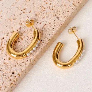 Orecchini a U placcati oro 18K con perle incastonate su sfondo in pietra neutra