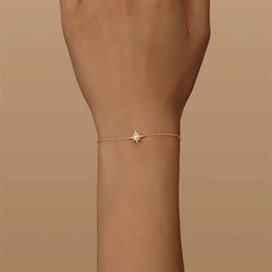 Gros plan détaillé d'un bracelet délicat en or avec étoile et perle porté au poignet