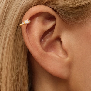 Κοντινό πλάνο χρυσού ear cuff με λουλούδια από κυβική ζιρκόνια στο πτερύγιο