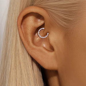 Close-up of a sterling silver moissanite conch piercing hoop worn on a model's ear