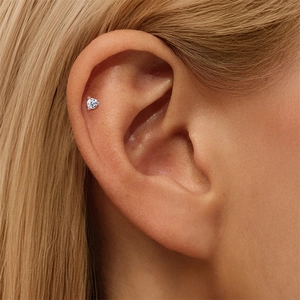 Macro shot of single round-cut moissanite stud earring set in silver prong on the upper ear