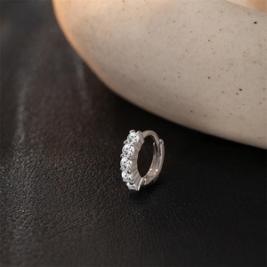 Gros plan d'une créole en argent S925 avec cinq pierres de moissanite serties griffes