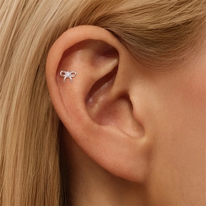Macro shot of silver bow helix piercing featuring a brilliant marquise moissanite stone
