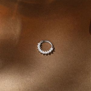 Macro detail of s925 silver clicker ring with pavé moissanite on leather background