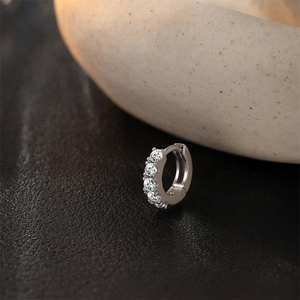 Vue macro d'une boucle d'oreille en argent S925 sertie de cinq zircons blancs étincelants
