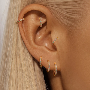 Close-up of golden S925 sterling silver hoop earrings with inlaid green and pink crystals
