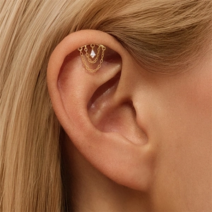 Primer plano de piercing hélix en plata S925 con cadenas doradas y remache con diamantes