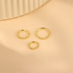 Makro-Detail von drei goldenen S925 Sterling Silber Perlen Piercingringen in verschiedenen Größen