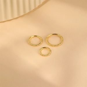 Detailed macro view of three S925 sterling silver gold-plated twisted hoop earrings