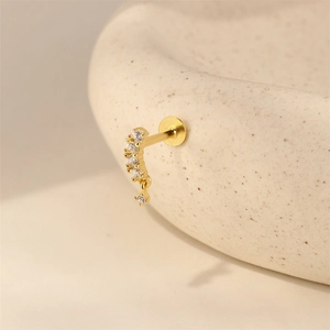 Detailopname van een vergulde gebogen labret met zirkonia en een hangende ronde hanger
