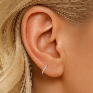 Macro shot of S925 silver pavé huggie earrings with sparkling stones on the ear lobe