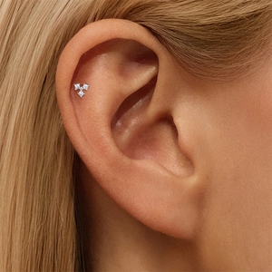 Macro de un piercing de oreja en plata S925 con tres piedras de moissanita redondas