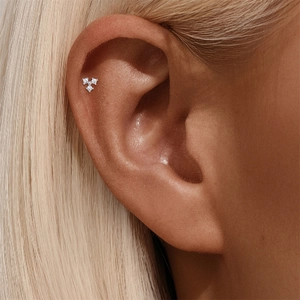 Detalle de piercing hélix de plata S925 con racimo de tres diamantes en la oreja humana