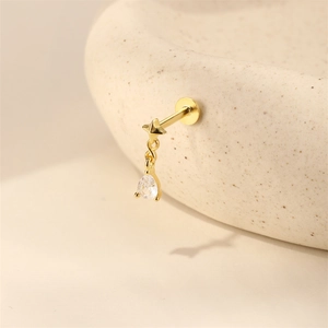 Macro-opname van gouden ster- en druppelzirkon-piercing op een keramische schaal