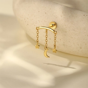 Detail von goldenem Stern- und Mondsichel-Ohrstecker auf eleganter Keramikschale