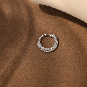 Macro detail of S925 silver hoop with a row of clear zircons and beaded edge design