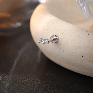 Detalle de piercing labret en plata S925 con tres piedras moissanita en arco elegante