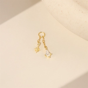 Detail of gold dangle earring featuring a delicate star charm and a kite-cut zircon stone