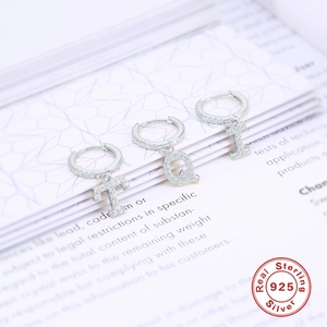 Dettaglio di orecchini in argento sterling 925 con lettere ricoperte di diamanti