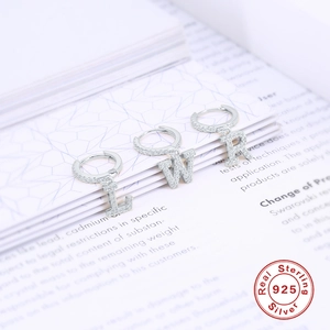 Dettaglio di orecchini a cerchio in argento S925 con lettere L, W e R con diamanti