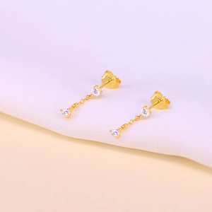 Vue macro des boucles d'oreilles en argent S925 doré avec zircon et fine chaîne pendante