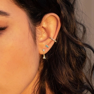 Gros plan de boucles d'oreilles S925 argent doré et pierres bleues sur l'oreille