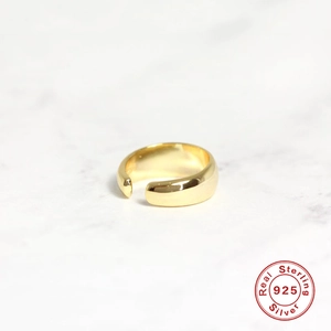 Gepolijste S925 sterling zilveren brede open ring in goudkleur op marmeren blad
