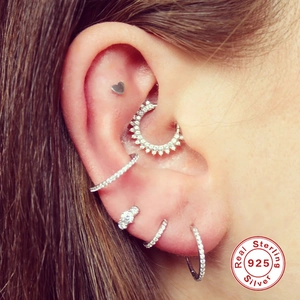 Gros plan d'un ensemble de piercings d'oreille en argent S925 avec zircons sur l'oreille