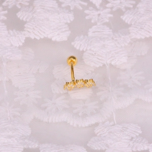 Close-up of golden curved barbell stud with sparkling white zircons on lace background