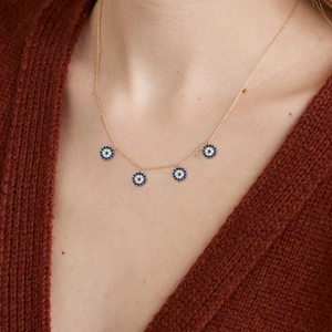 Close-up of S925 silver evil eye necklace with four gold charms on a knitted sweater