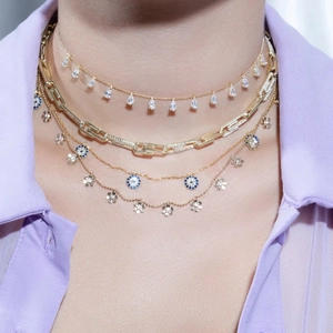 Detail of layered gold necklaces featuring blue evil eye and droplet pendants