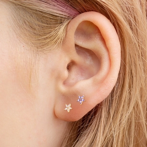 Detailed macro shot of small five-petal zircon flower stud earrings in white and purple