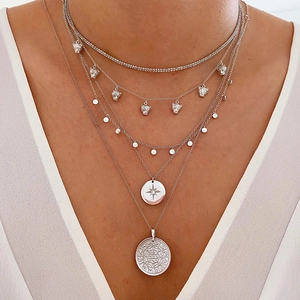 Detail of multi-layered silver S925 necklaces featuring leopard heads and star coin pendants