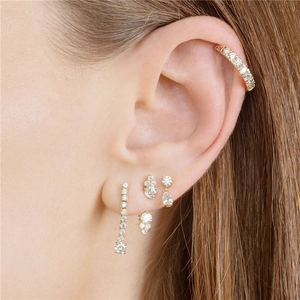 Dettaglio di orecchini a lobo in argento S925 dorato e ear cuff con diamanti sul orecchio